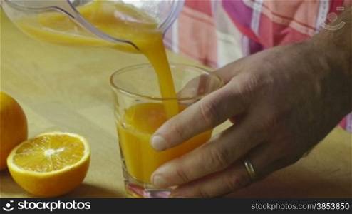 Closeup of man using citrus-fruit squeezer and pouring orange juice in glass. Sequence