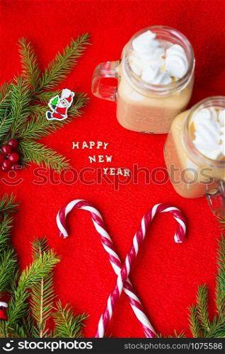 Closeup of marshmellou cocoa and candy on a red background. The inscription Happy New Year.. Closeup of marshmellou cocoa and candy on a red background. The inscription Happy New Year