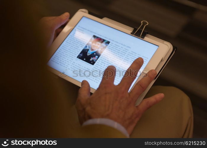 Closeup of mature hands holding tablet. Teacher with students in classroom