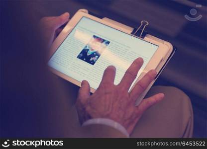 Closeup of mature hands holding tablet. Teacher with students in classroom
