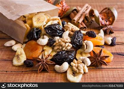 Closeup of mix of dried fruits and nuts in a paper bag over a rustic table. Closeup of mix of dried fruits and nuts in a paper bag