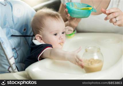 Closeup of mother feeding baby boy with porridge