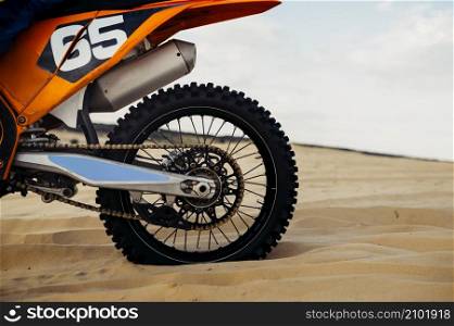 Closeup of motocycle wheel over sand terrain. Motocross competition. Motorsport extreme recreation. Closeup of motorbike wheel over sand terrain