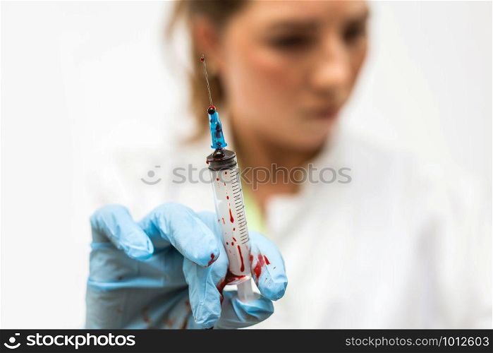 Closeup of nurse&rsquo;s hands with syringe of blood for cure disease, leaking blood horror scene medical. Closeup of nurse&rsquo;s hands with syringe of blood for cure disease, leaking blood horror scene