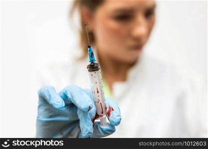 Closeup of nurse&rsquo;s hands with syringe of blood for cure disease, leaking blood horror scene medical. Closeup of nurse&rsquo;s hands with syringe of blood for cure disease, leaking blood horror scene