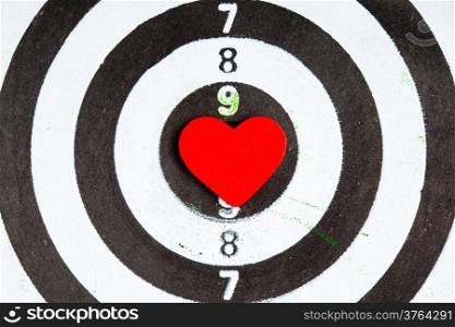 Closeup of old black and white target with red heart symbol bullseye as love background. Valentines day.