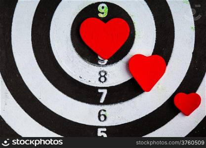 Closeup of old black and white target with red hearts symbols bullseye as love background. Valentines day.
