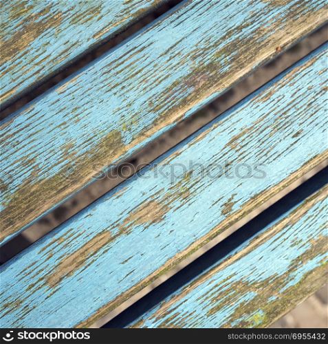closeup of old grungy bench planks with peeling blue paint