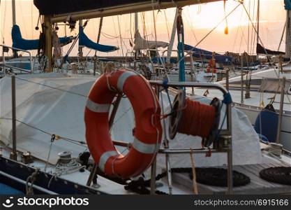 Closeup of Orange Lifebuoy and Rolled Rope on Sailing Boat: Dock Seaside at Sunset