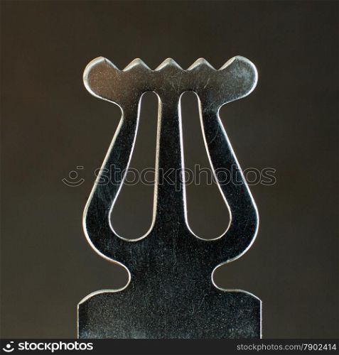 closeup of ornament on old metal music stand against dark background
