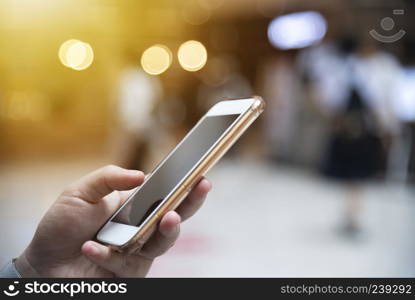 Closeup of people hand working online in mobile with blurred city light on the street background. Modern wireless connection technology for lifestyle and business. Network connection and communication