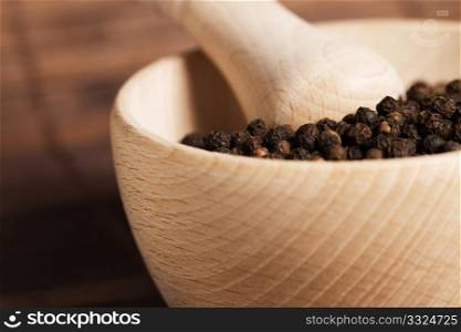 closeup of peppercorns in a wooden mortar. closeup of peppercorns in a wooden mortar with a very soft focus