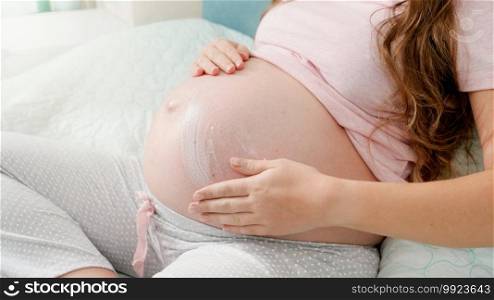 CLoseup of pregnant woman applying moisturizing creme against stretch marks on big belly. Concept of expecting baby, pregnancy and healthcare. CLoseup of pregnant woman applying moisturizing creme against stretch marks on big belly. Concept of expecting baby, pregnancy and healthcare.