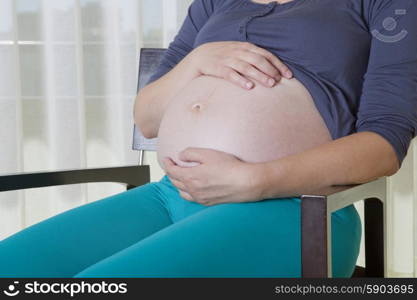 Closeup of pregnant woman on a chair