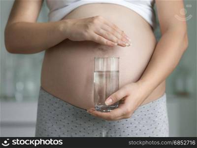 Closeup of pregnant woman posing with glass of water
