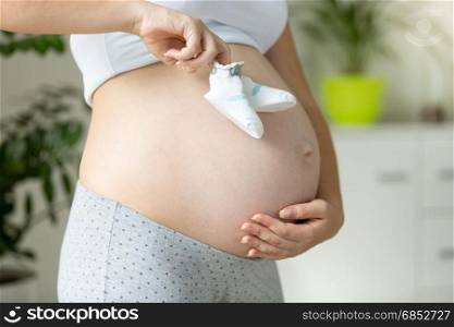 Closeup of pregnant woman pretending to walk with child socks on her belly