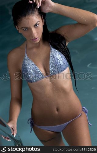 Closeup of pretty young lady have fun and posing while relaxing in the swimming pool in luxury hotel