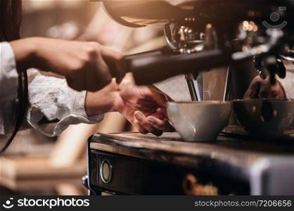 Closeup of professional female barista hand making cup of coffee with coffee maker machine in restaurant or coffee shop. People and lifestyles. Business food and drink concept. Shop owner theme