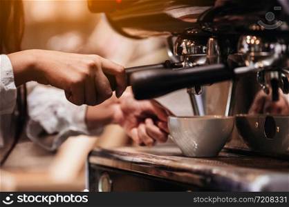 Closeup of professional female barista hand making cup of coffee with coffee maker machine in restaurant or coffee shop. People and lifestyles. Business food and drink concept. Shop owner theme