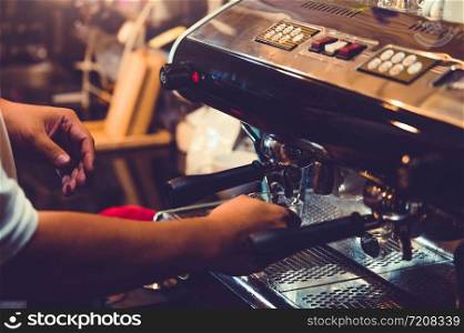 Closeup of professional male barista hand making cup of coffee with coffee maker machine in restaurant or coffee shop. People and lifestyles. Business food and drink concept. Shop owner theme