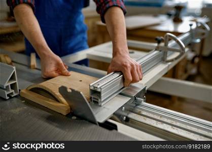 Closeup of professional male carpenter cutting wooden board on circular saw workbench at workshop. Closeup of carpenter cutting wooden board on circular saw workbench