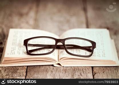 Closeup of reading glasses on the old book