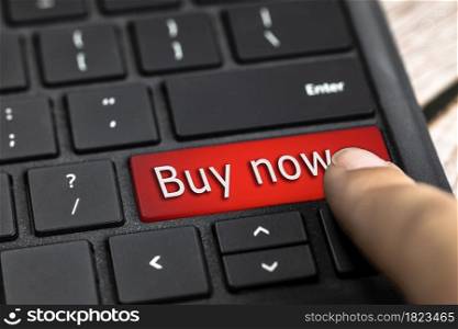 Closeup of red computer keyboard key with the text Buy now in white Letters, Online shopping, technology and sale concept. Closeup of finger on red computer keyboard key with the text Buy now in white Letters, Online shopping, technology and sale concept