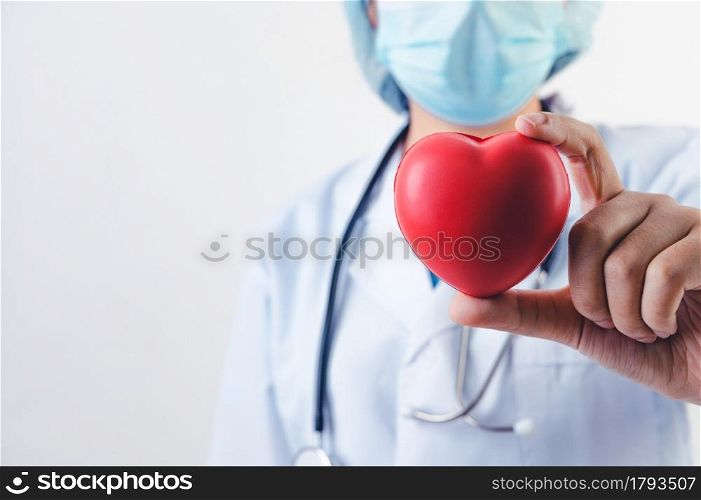 Closeup of red heart in doctor hand with stethoscope on white background. Medical people and cardio practitioner concept. Heart donation and life rescue health care theme.
