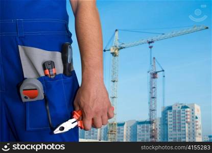 Closeup of repairman with pliers on building background
