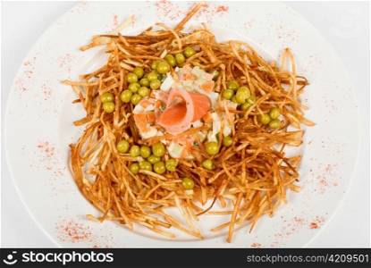 Closeup of salad with salmon fish at fried sliced potato with carrot and peas dressed by tomato sauce with cognac