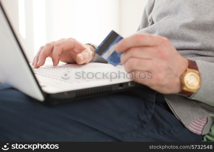 Closeup of senior male hands with credit card and laptop