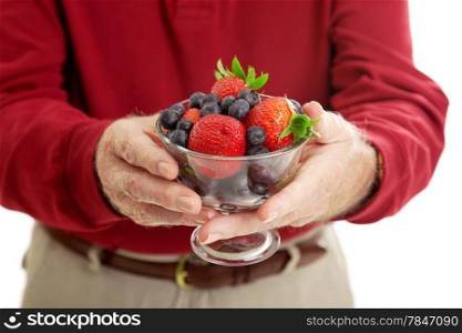 Closeup of senior man&rsquo;s hands holding a bowl of healthy, antioxidant rich berries.