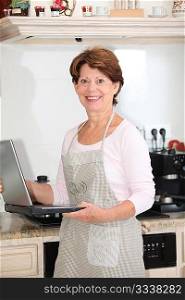 Closeup of senior woman in kitchen with laptop computer