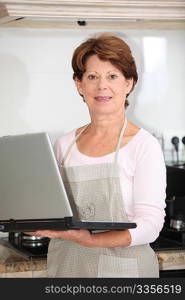 Closeup of senior woman in kitchen with laptop computer