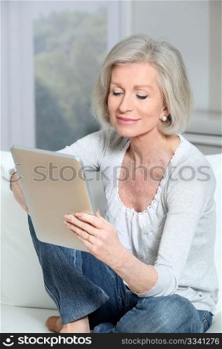 Closeup of senior woman sitting on sofa with electronic pad