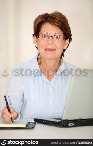 Closeup of senior woman working in office with laptop computer