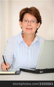 Closeup of senior woman working in office with laptop computer