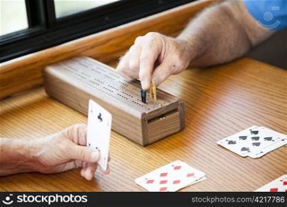 Closeup of seniors hands playing a game of cribbage.