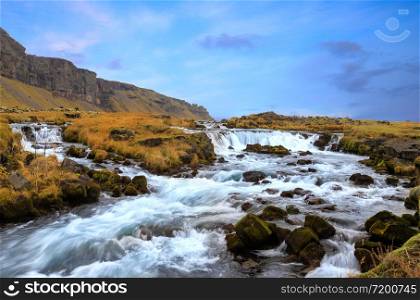 Closeup of small waterfall cascade , Iceland with smooth long exposure blurry blurred water flowing in green mossy summer