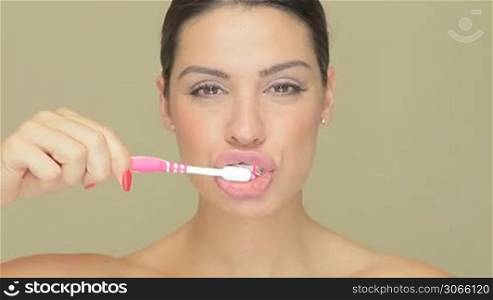 Closeup of smiling beautiful woman with a toothbrush and toothpaste on a light brown studio background