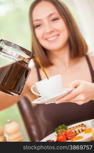 Closeup of smiling brunette woman pouring a cup of coffee