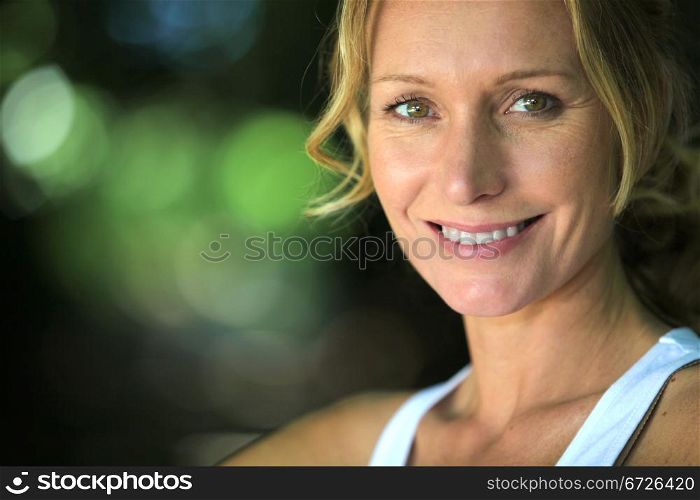 Closeup of smiling woman in leafy environment
