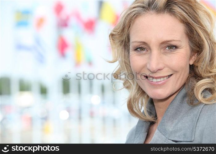 Closeup of smiling woman with international flagpoles in the distance