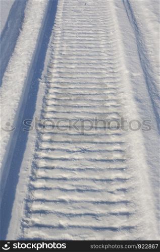 Closeup of snowmobile trail in snowy field