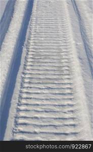 Closeup of snowmobile trail in snowy field
