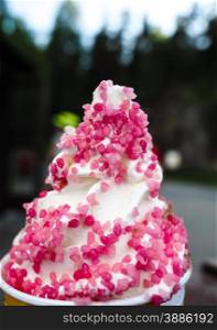 Closeup of soft serve ice cream with fresh pink frizzle outdoors