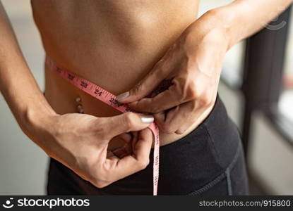 Closeup of sport happy slim woman using waist tape line in fitness gym sport club training center background. Success lifestyle of people workout exercise activity. Diet and weight loss