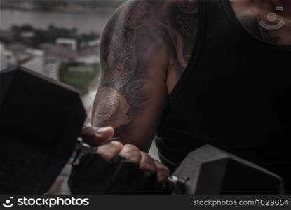 Closeup of Strong bodybuilder, power athletic man in training pumping up muscles with dumbbell in gym or fitness club.