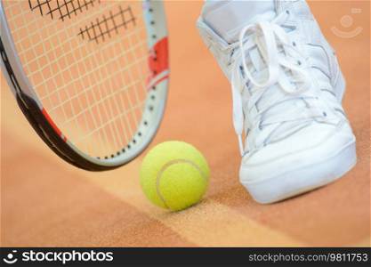 Closeup of tennis racket, ball and shoe