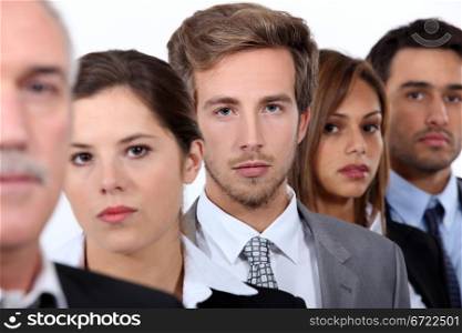 Closeup of the faces of a group of serious young executives and their older boss